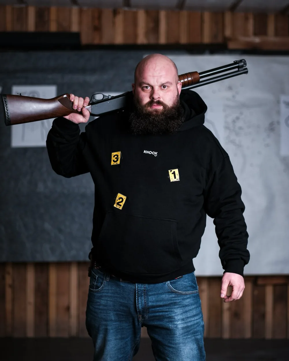Šaudyklos instruktorius su KNOCK džemperiu ir šautuvu